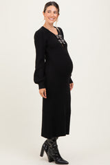 woman wearing a black ribbed maternity dress with long sleeves and a statement necklace, showing her baby bump