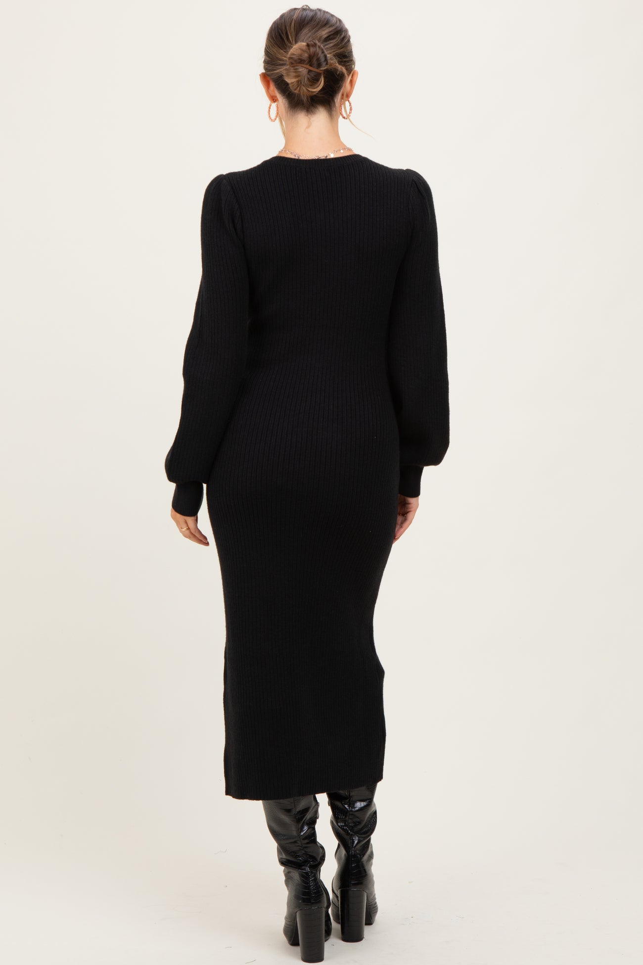 woman wearing a black ribbed maternity dress with long sleeves and a fitted silhouette, viewed from the back