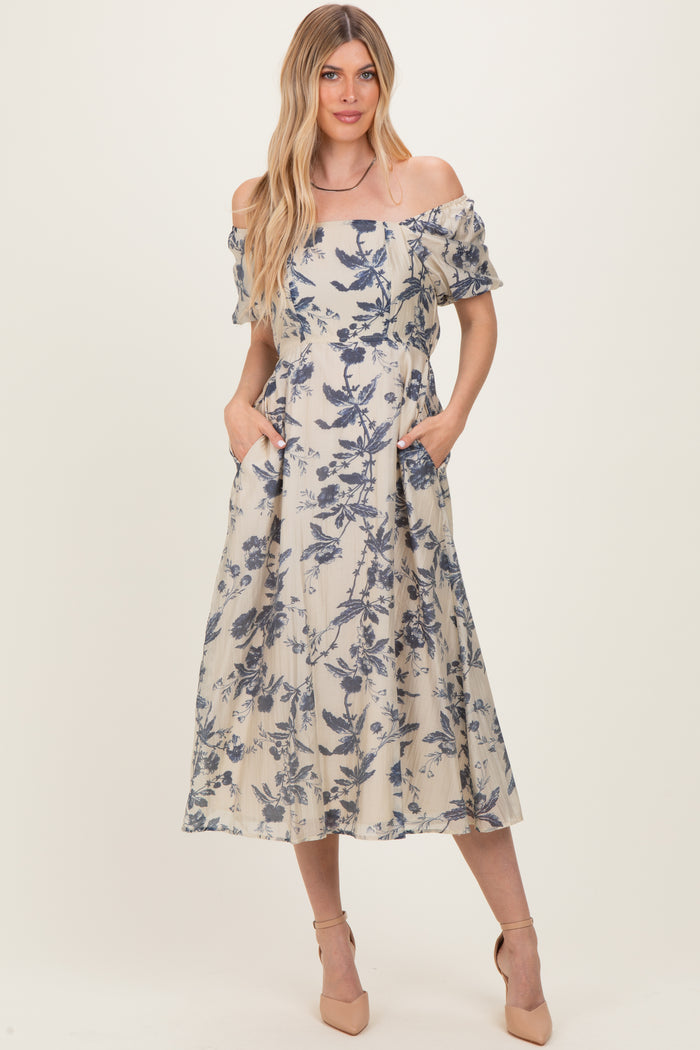woman wearing a floral off-the-shoulder midi dress with pockets and a light beige background