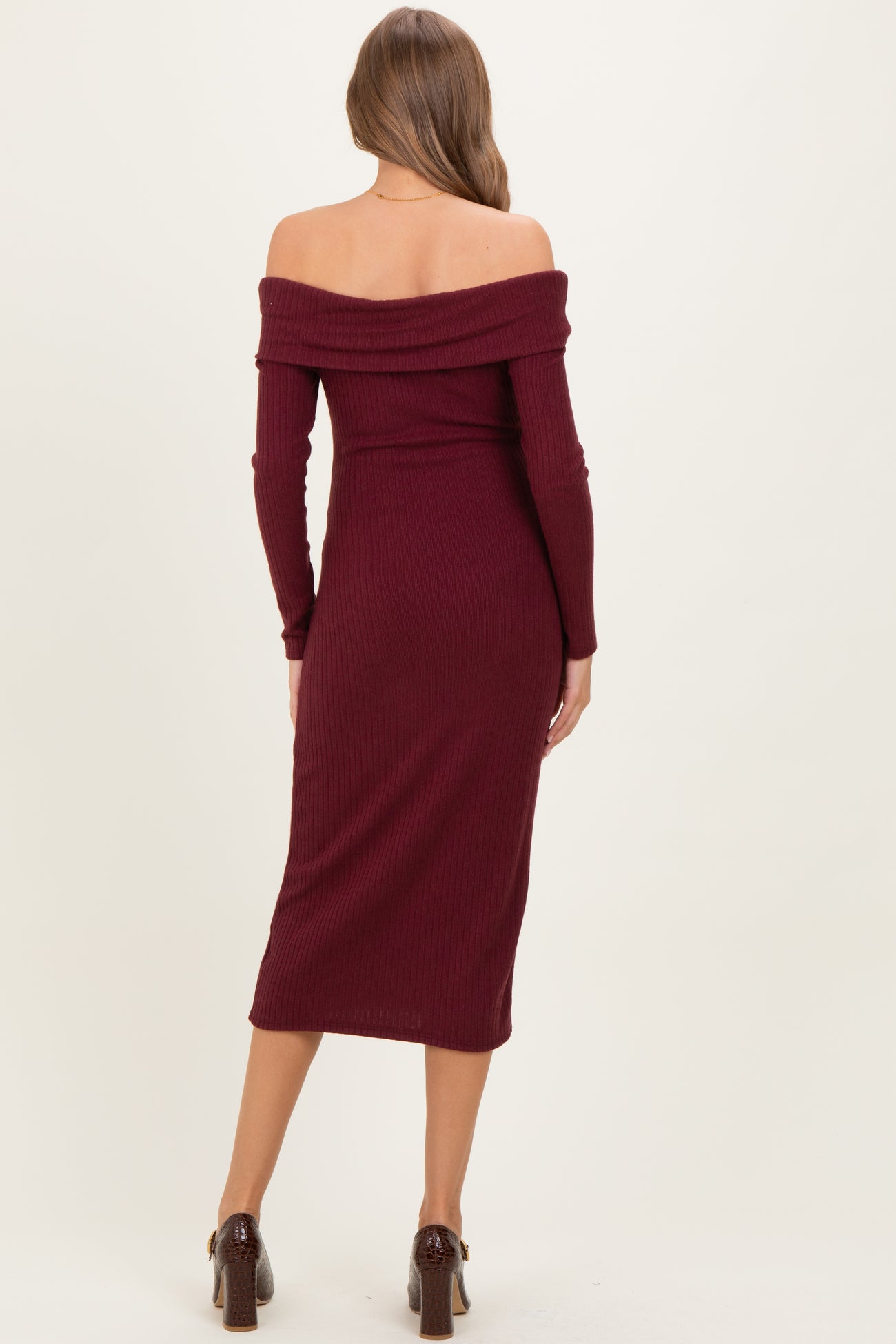 woman wearing a burgundy off-the-shoulder ribbed maternity dress with long sleeves and a fitted silhouette