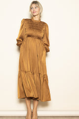 woman wearing a mustard yellow long sleeve smocked maxi dress with a tiered skirt and a relaxed fit