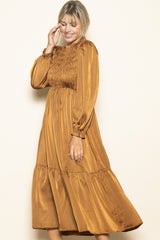 woman wearing a mustard gold smocked long sleeve midi dress with a tiered skirt and puffy sleeves