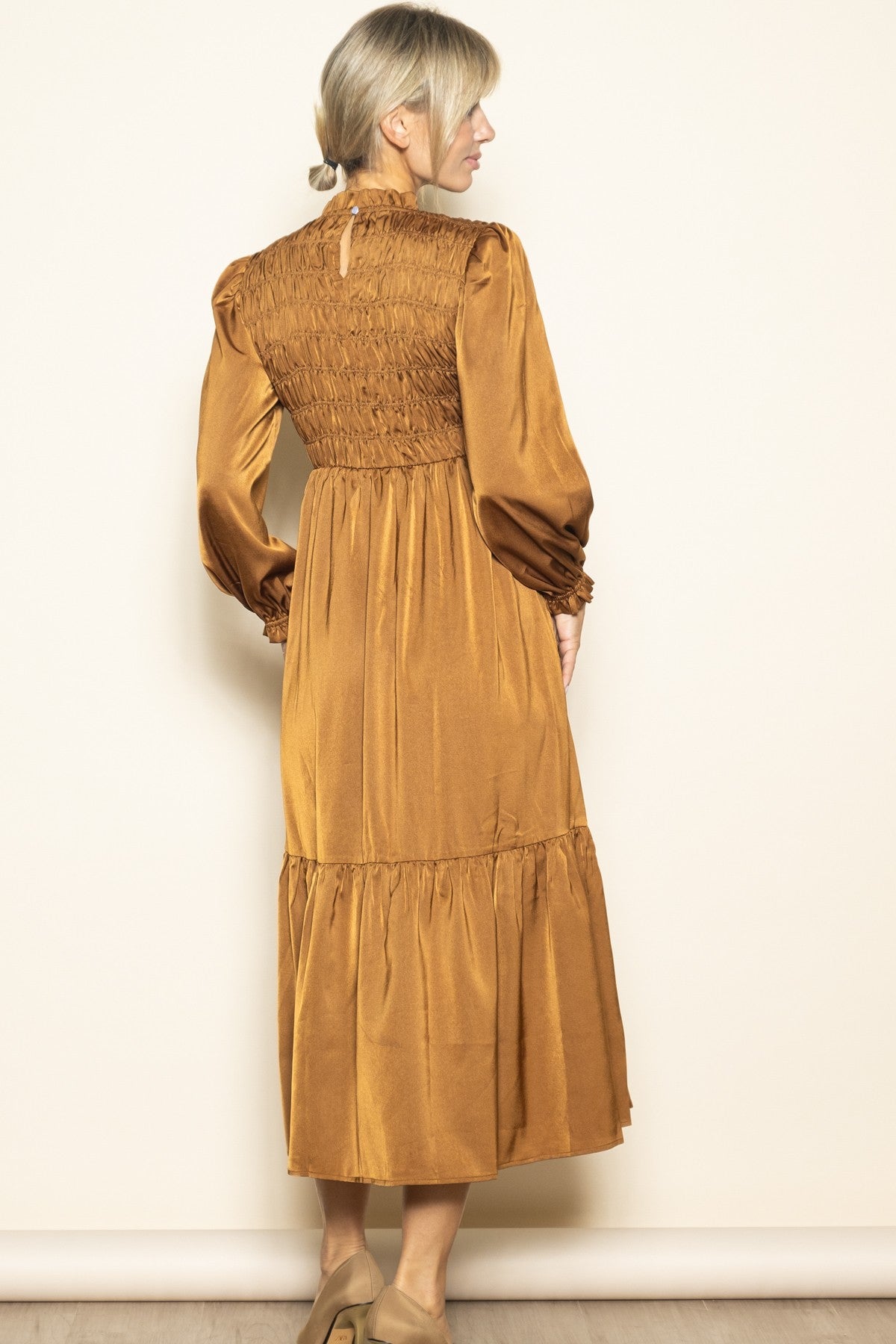 woman wearing a long brown smocked back maxi dress with puff sleeves and a tiered skirt