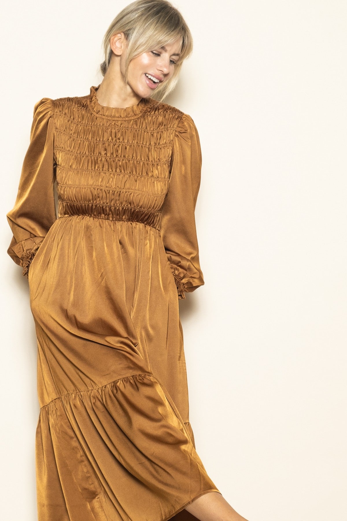 woman wearing a rust-colored long sleeve smocked dress with a tiered skirt and ruffled sleeves
