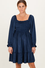 woman wearing a navy blue smocked mini dress with long sleeves and a tiered skirt