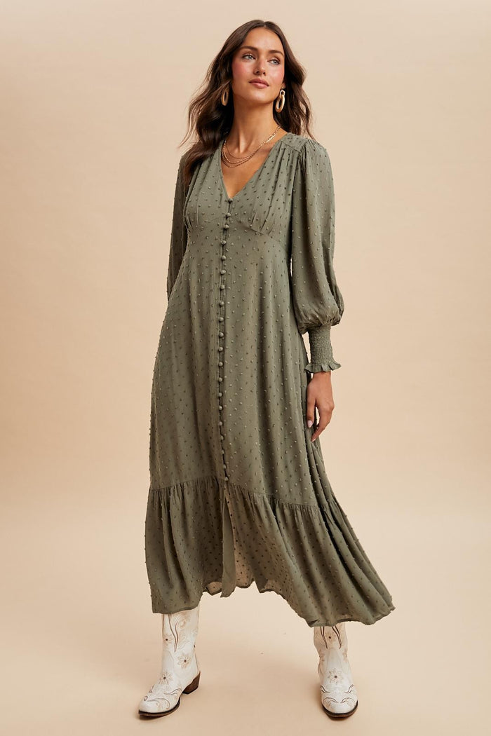 woman wearing an olive green long sleeve button-up dress with a tiered skirt and white cowboy boots
