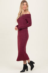 woman wearing a burgundy off-the-shoulder long sleeve midi dress paired with black ankle boots
