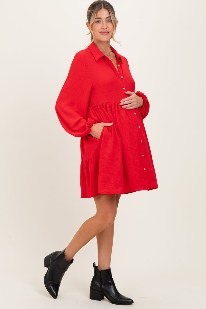 woman wearing a red maternity dress with a button-up front and pockets, showing her baby bump