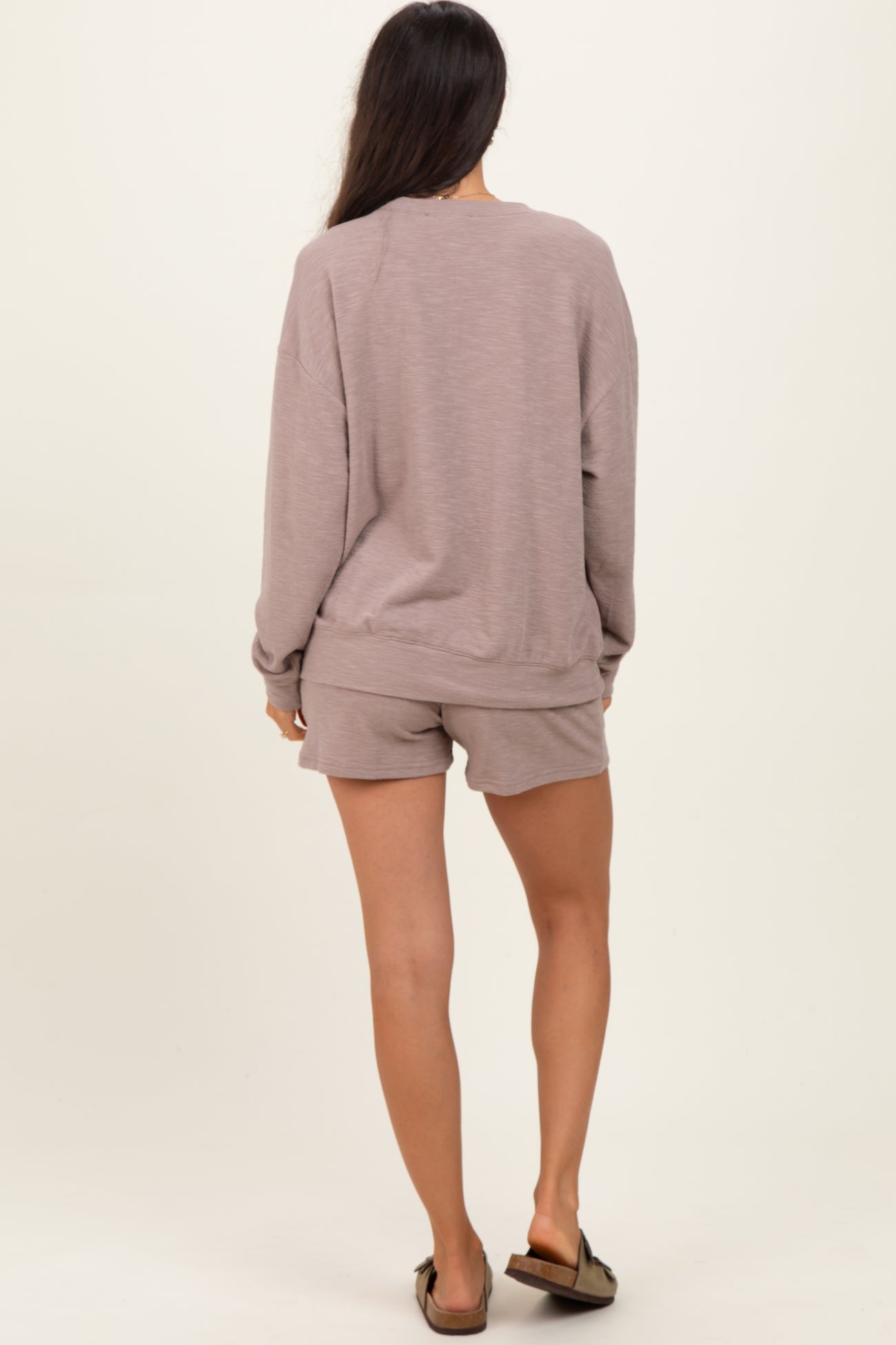 woman wearing a taupe casual sweatshirt and matching shorts, viewed from the back