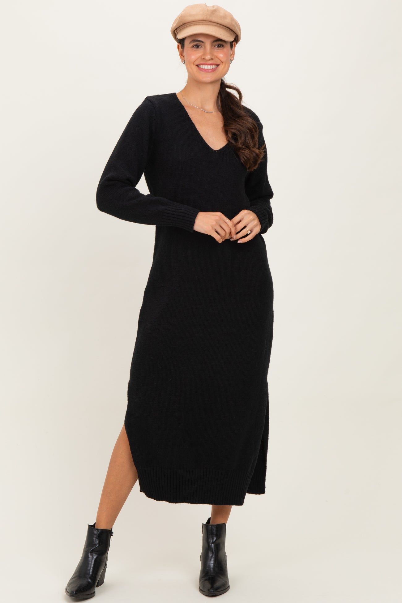 woman wearing a black long sleeve v-neck sweater dress with side slits and ankle boots