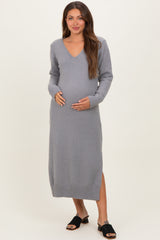 woman wearing a gray long sleeve maternity sweater dress with a v-neck and side slit, cradling her baby bump