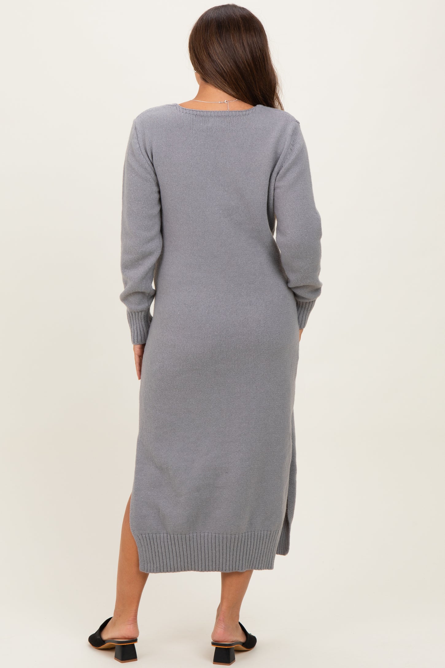 woman wearing a gray long sleeve maternity dress with side slits and a fitted silhouette, seen from the back