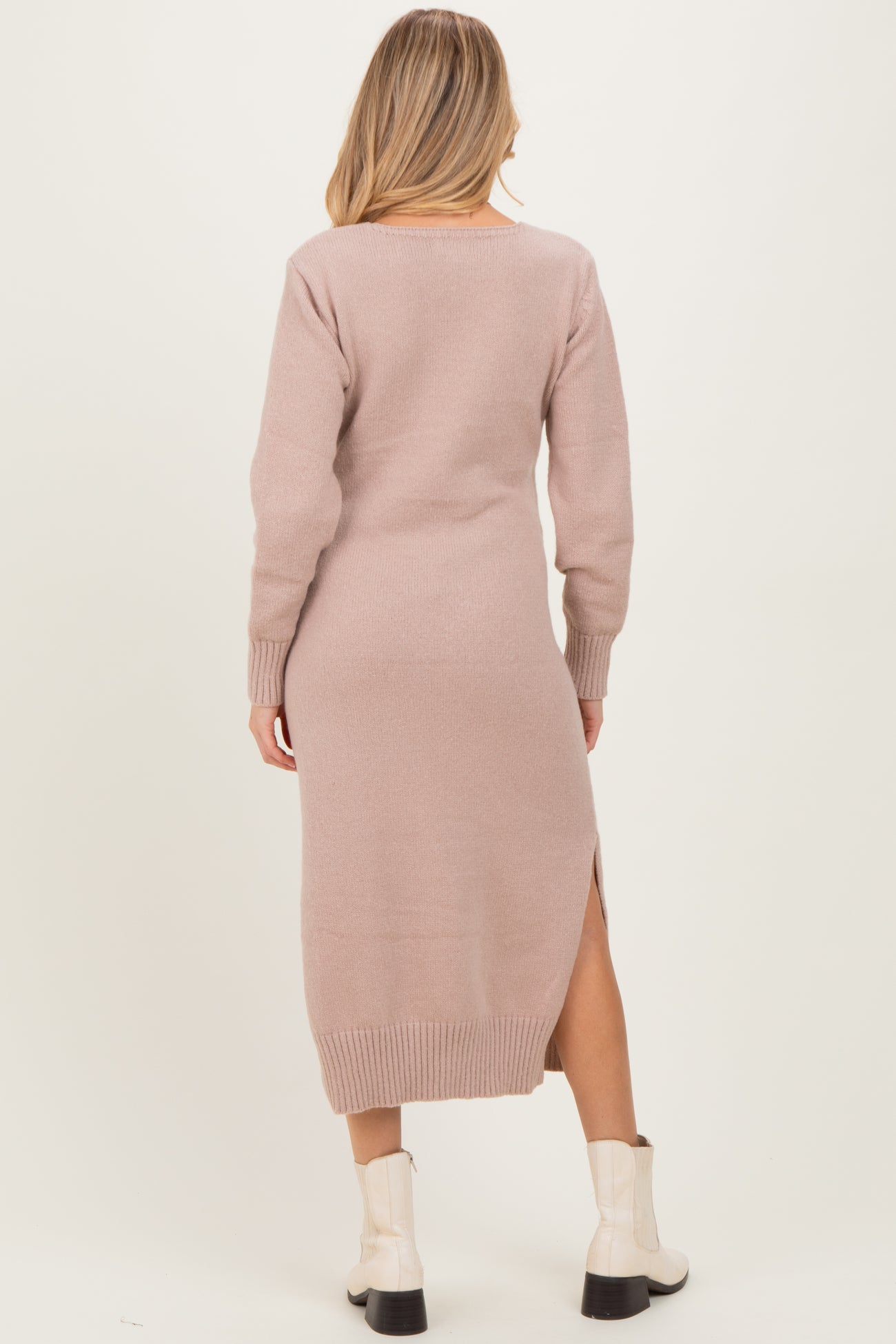 woman wearing a light pink long sleeve maternity sweater dress with side slits and a relaxed fit