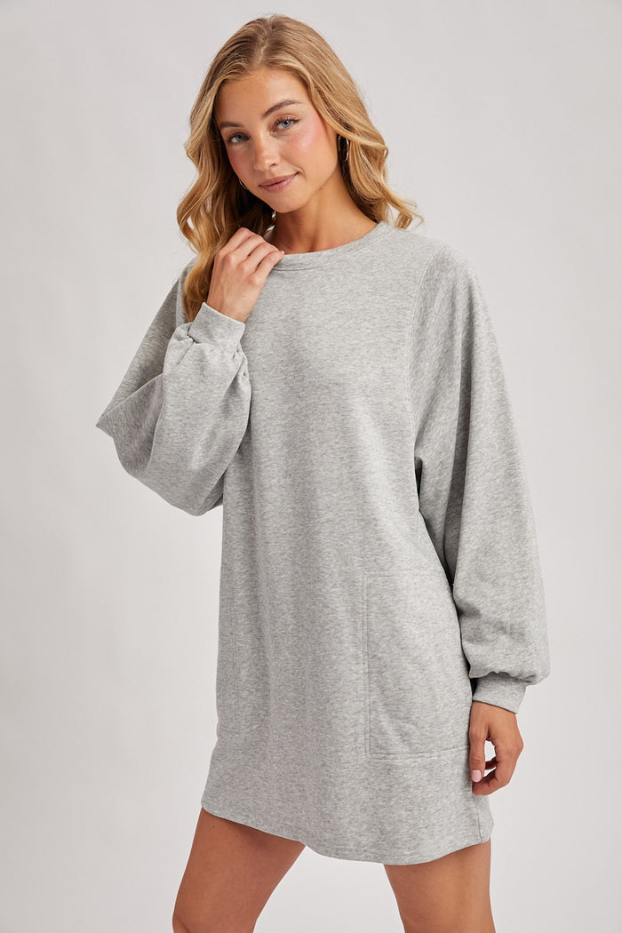 woman wearing a gray long sleeve sweatshirt dress with a relaxed fit and side pockets