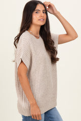 woman wearing a beige knitted oversized sweater with short sleeves and a relaxed fit