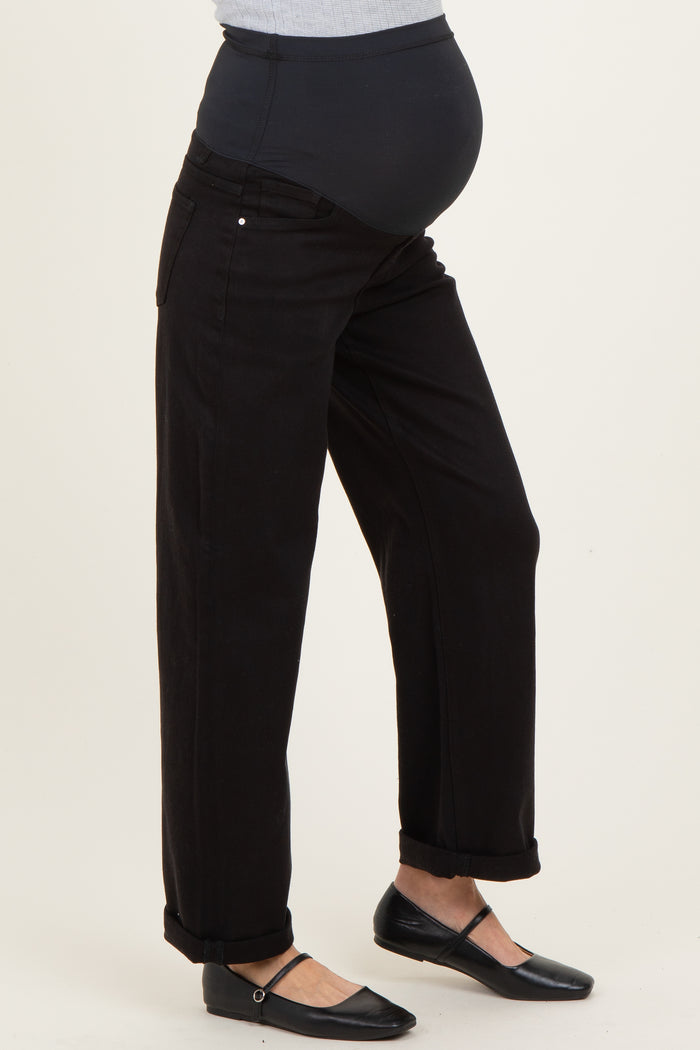 woman wearing black maternity jeans with a high waistband and rolled cuffs, revealing a baby bump