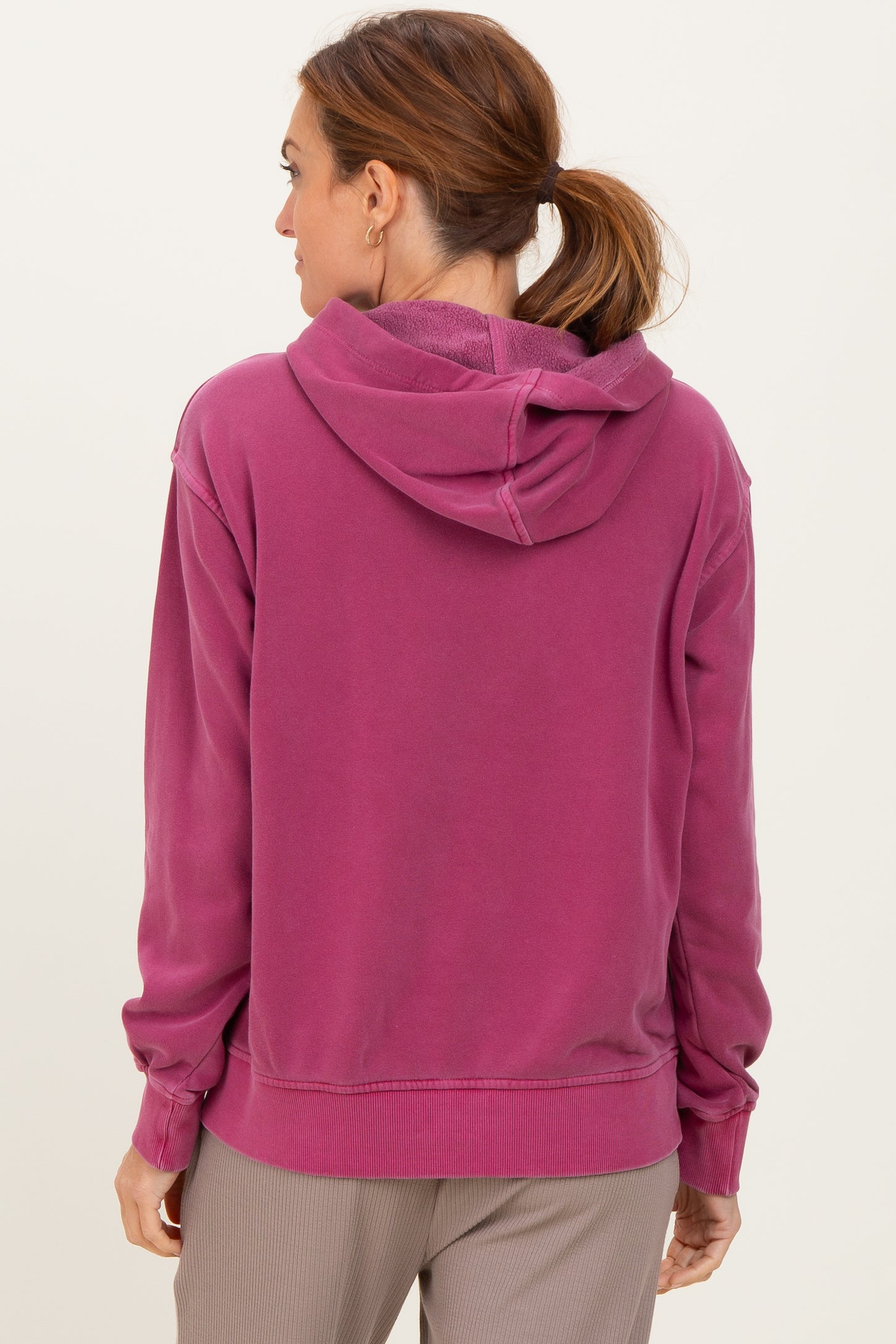 woman wearing a pink hoodie with a relaxed fit and a drawstring hood, viewed from the back