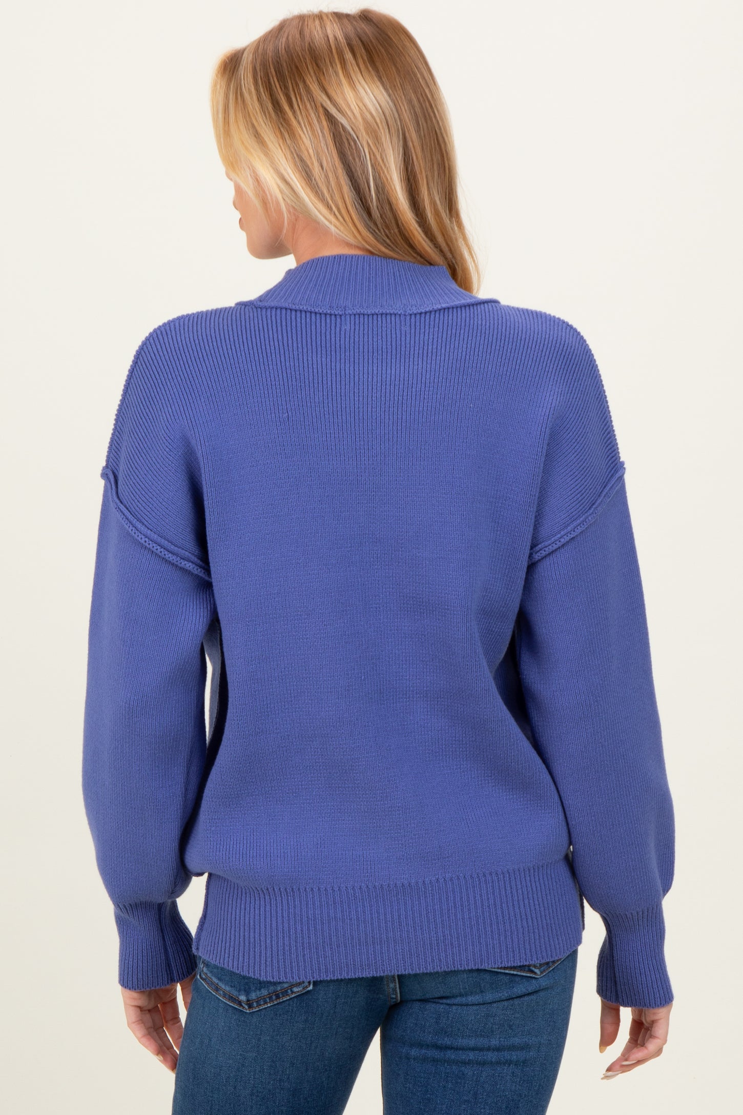 woman wearing a blue oversized maternity sweater with a relaxed fit and dropped shoulders, seen from the back