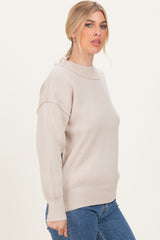woman wearing a beige oversized ribbed sweater paired with blue jeans