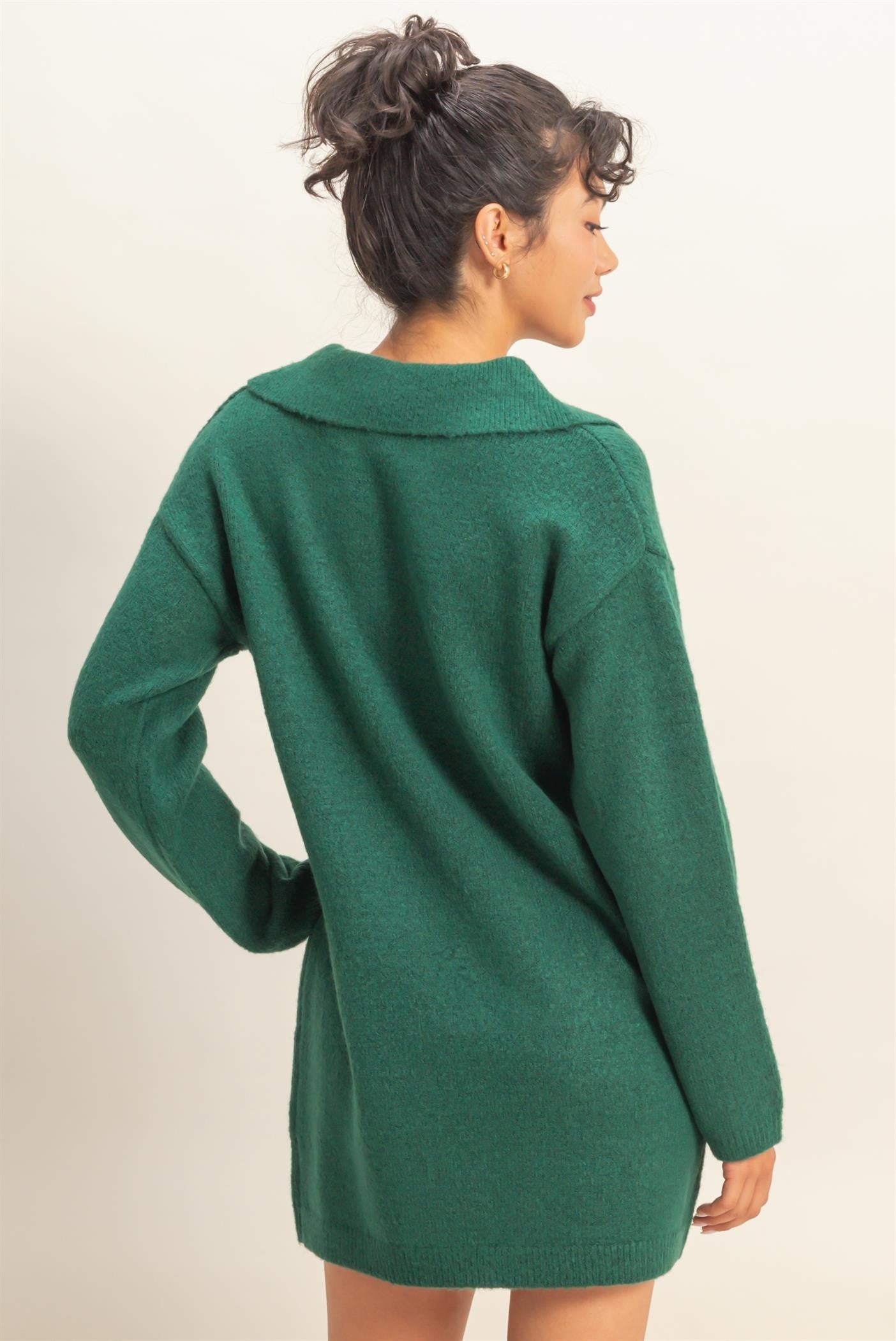 woman wearing a green oversized sweater dress with a collared neckline and long sleeves, shown from the back