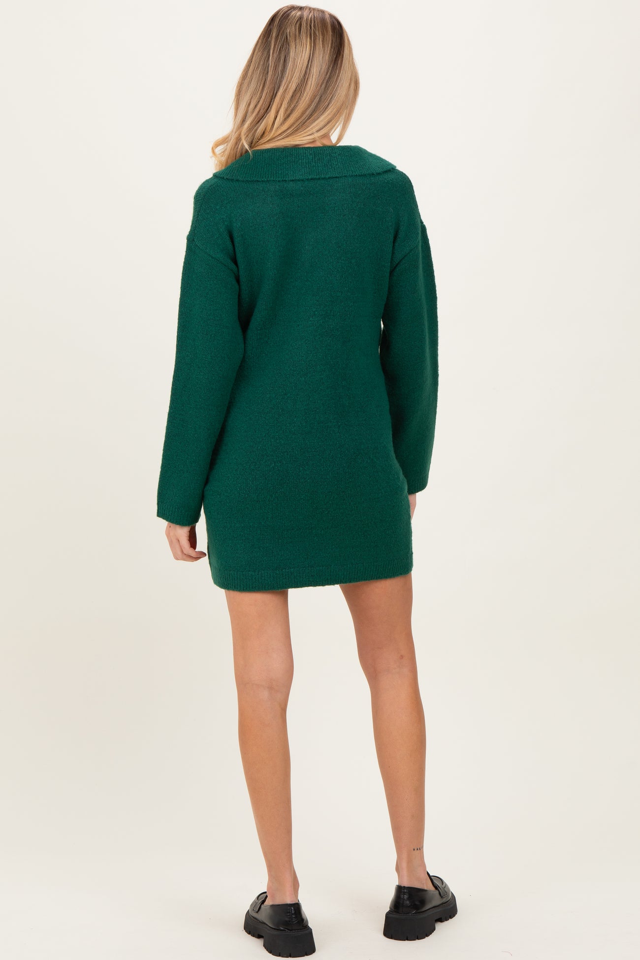 woman wearing a dark green maternity sweater dress with long sleeves, viewed from the back