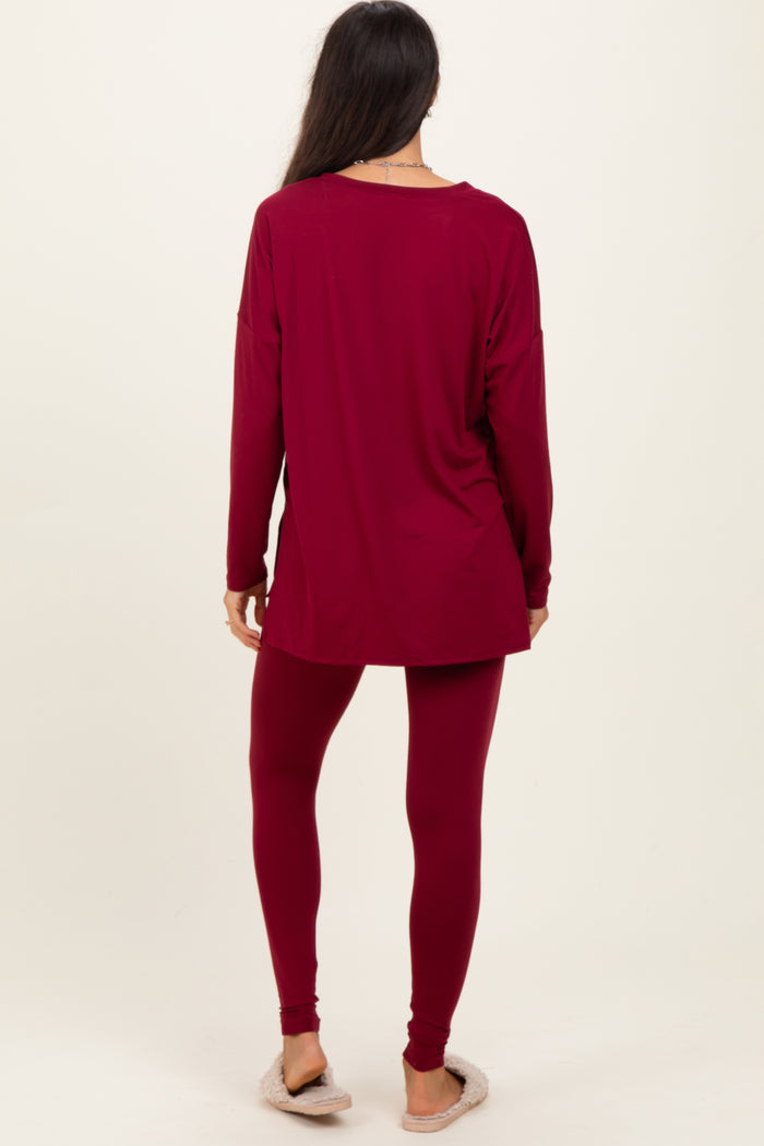 woman wearing a maroon long sleeve top and matching leggings, standing with her back to the camera