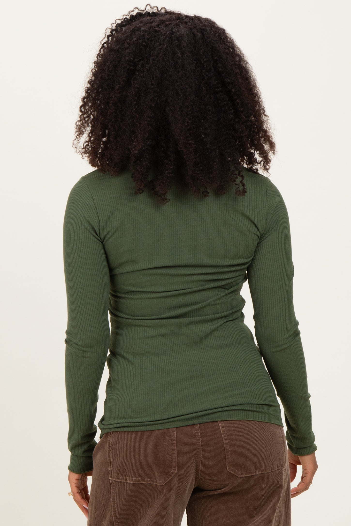 woman wearing a fitted long sleeve olive green ribbed top, seen from the back