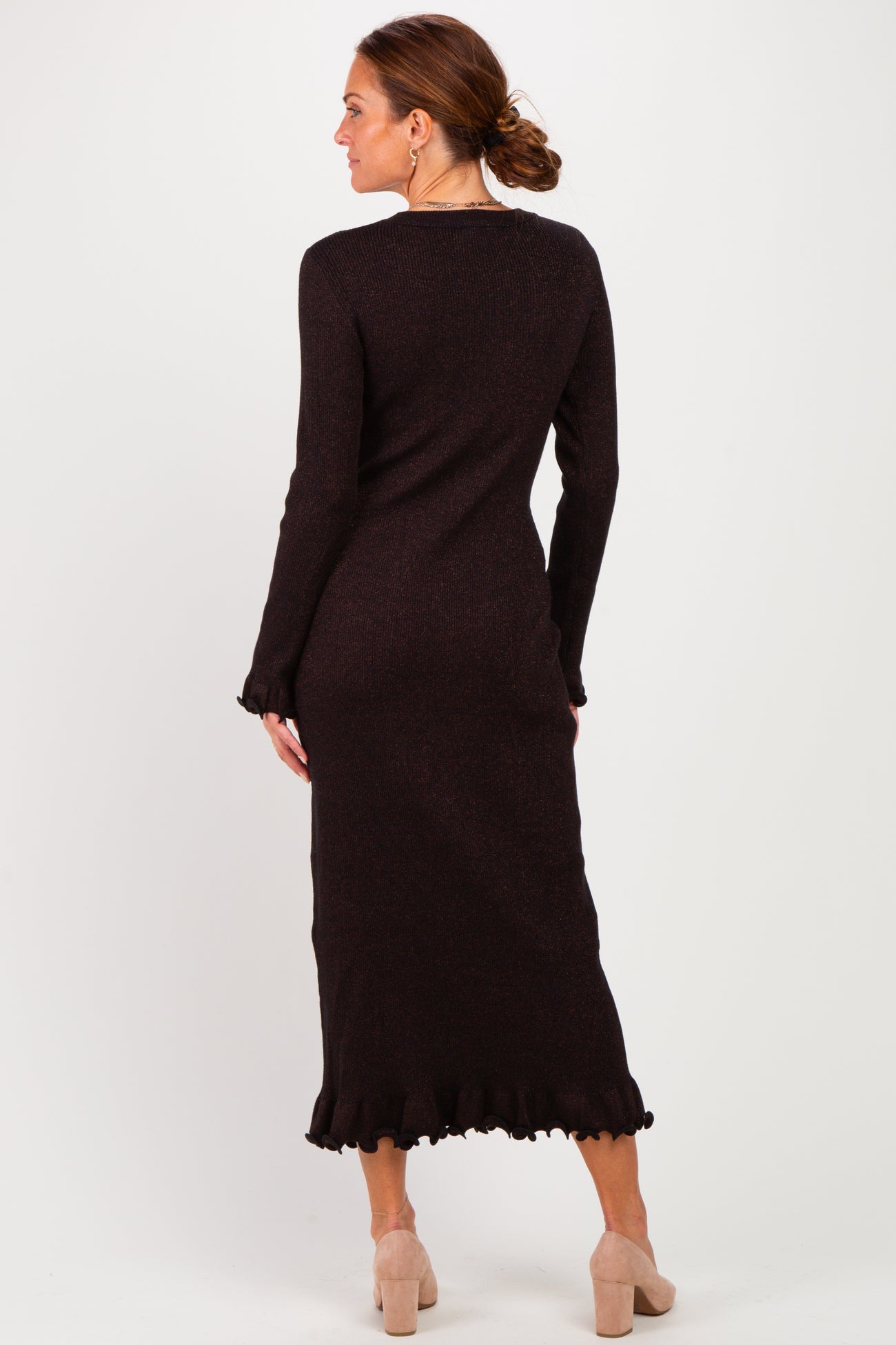 woman wearing a dark brown long sleeve knit dress with ruffled hem иnd back view standing against a plain background