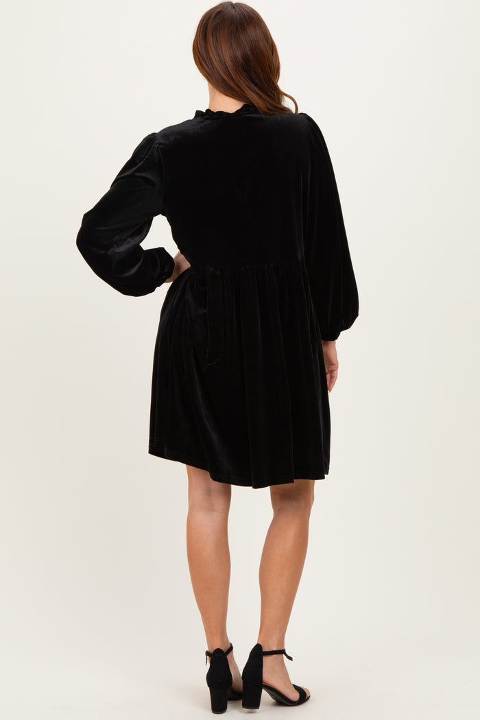woman wearing a black velvet mini dress with puff sleeves and a gathered waist, view from the back