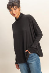 woman wearing a black turtleneck loose fit sweater with long sleeves and blue jeans