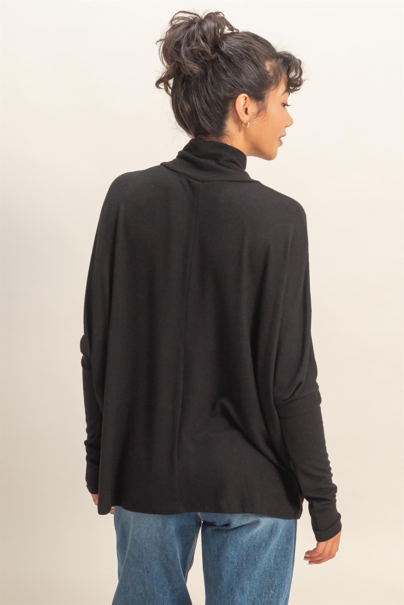 woman wearing a black turtleneck sweater with a relaxed fit and long sleeves, seen from the back