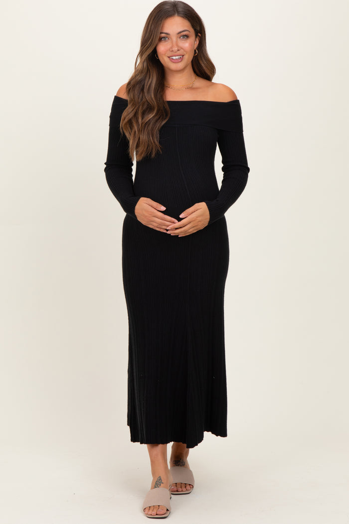 woman wearing a black off-the-shoulder ribbed maternity dress and holding her baby bump
