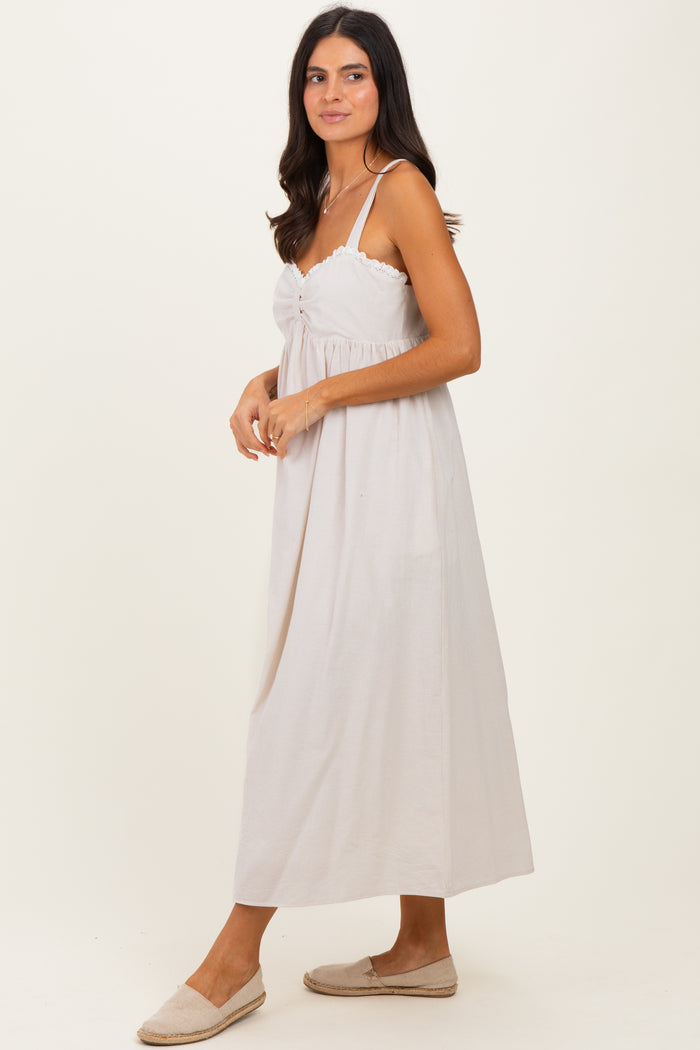 woman wearing a light beige striped maxi dress with adjustable straps and a gathered front detail