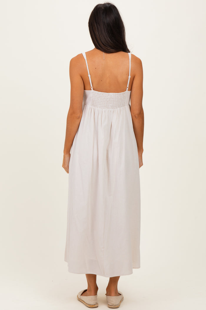 woman wearing a light beige striped maxi dress with a smocked back and spaghetti straps, viewed from the back