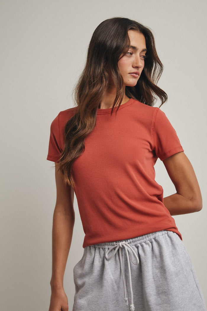 woman wearing a rust colored short sleeve t-shirt and gray sweatpants