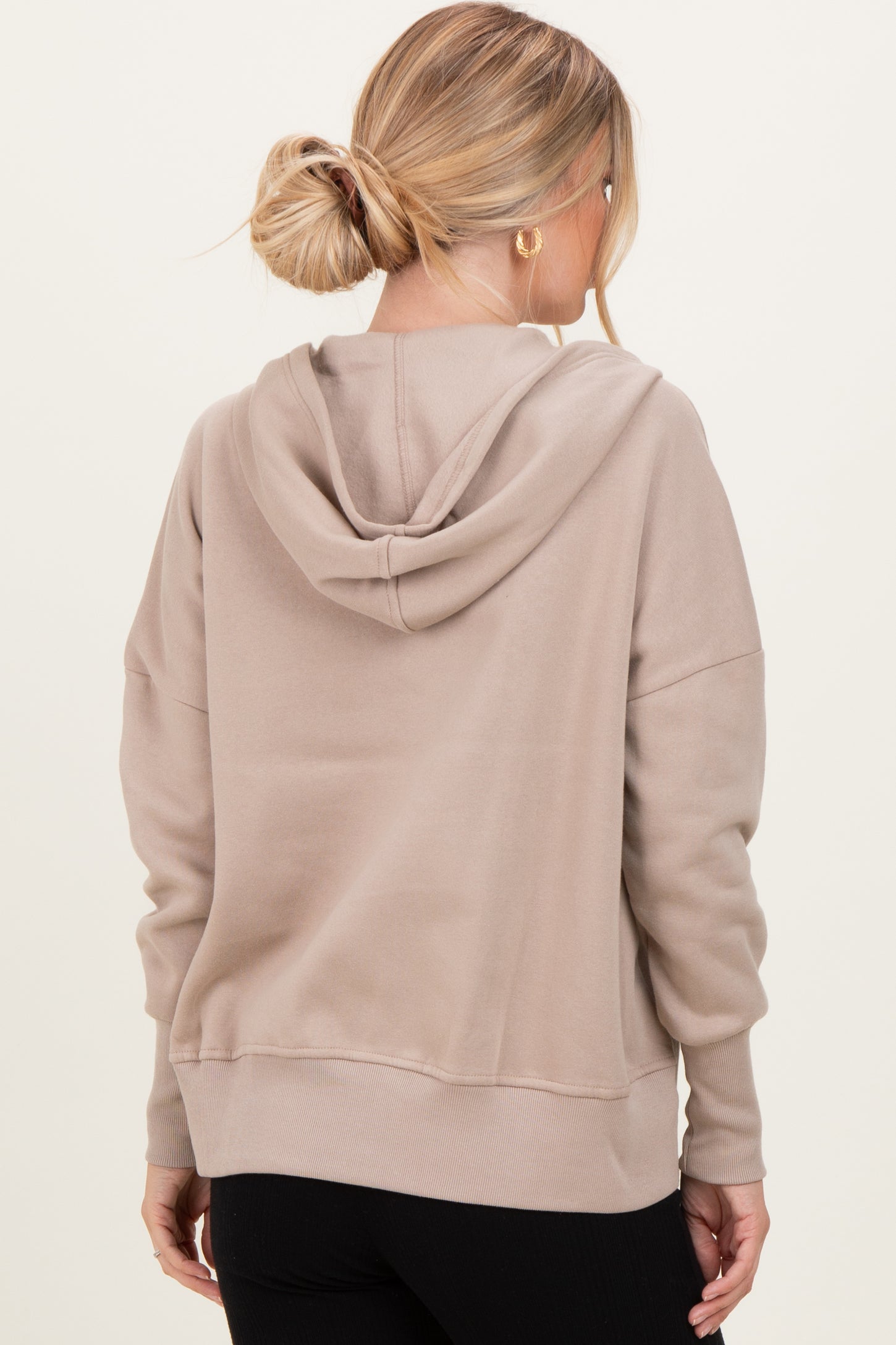 woman wearing a beige oversized hoodie with a back hoodie and ribbed cuffs