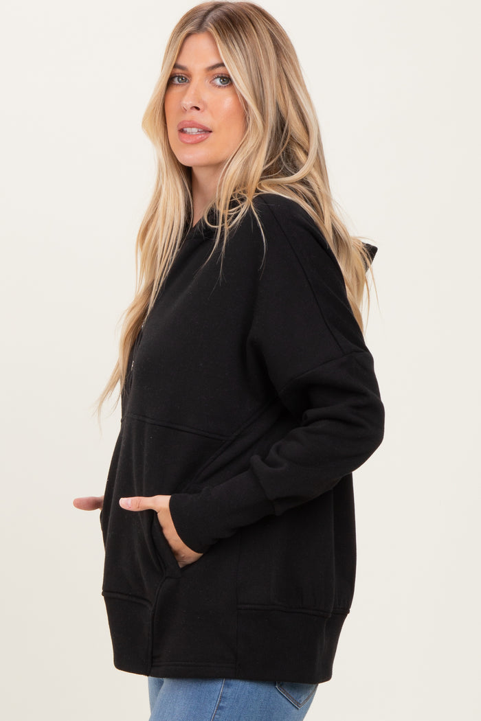 woman wearing a black oversized hoodie with kangaroo pockets and a hood, styled with light blue jeans