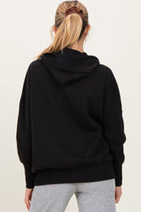 woman wearing a black maternity hoodie with a relaxed fit and hood, seen from the back