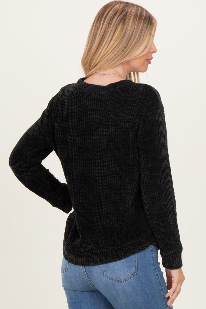 woman wearing a black ribbed long sleeve shirt with a relaxed fit and a round neckline, seen from the back