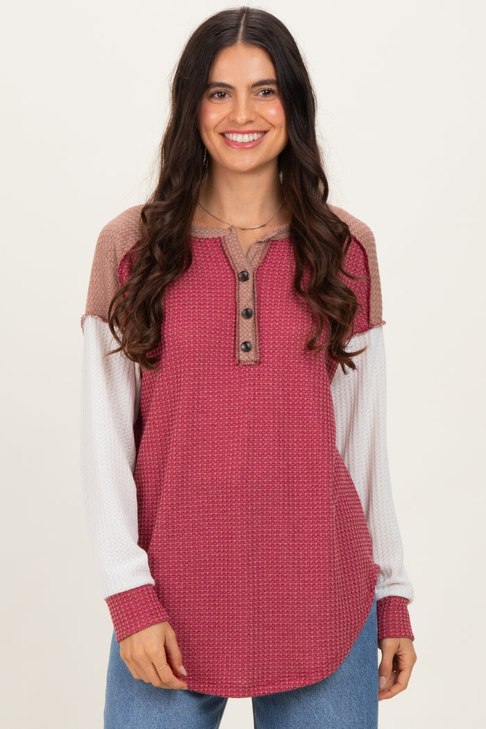 woman wearing a burgundy and beige color-blocked long sleeve top with buttons and a relaxed fit