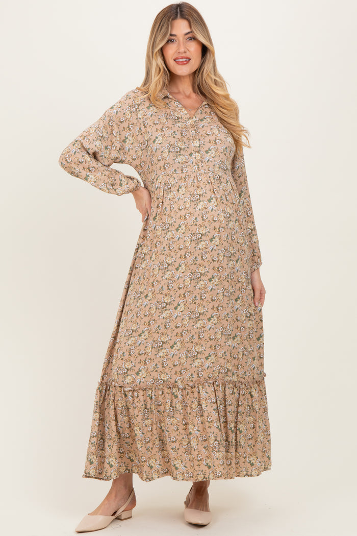 woman wearing a beige floral maternity dress with long sleeves and a tiered hem, showcasing her baby bump