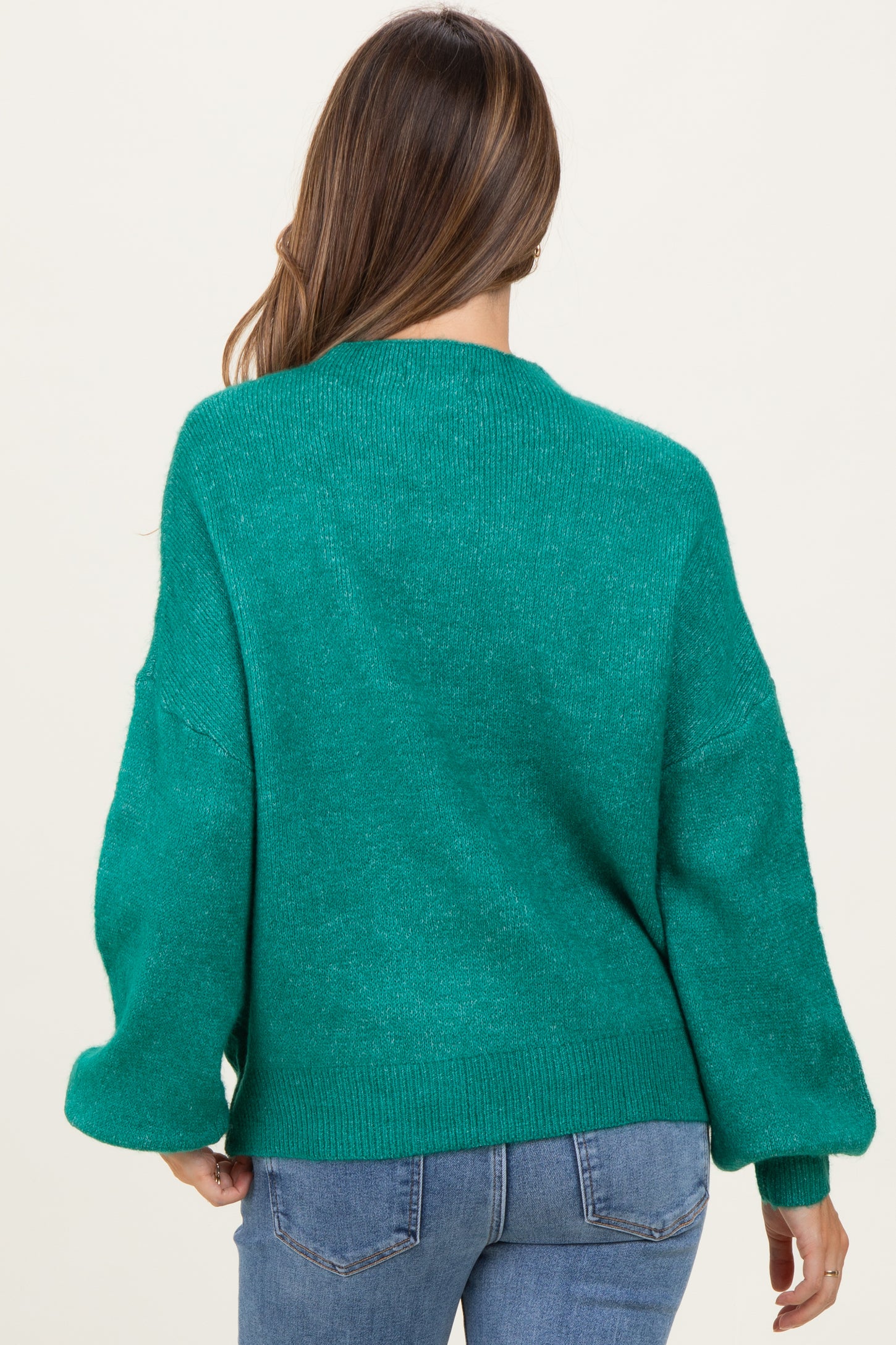 woman wearing a green oversized maternity sweater with loose sleeves, view from the back