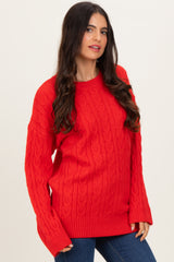 woman wearing a red cable knit sweater with long sleeves and ribbed hem paired with blue jeans