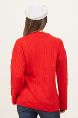 woman wearing a red cable knit maternity sweater, seen from the back, with a relaxed fit and long sleeves