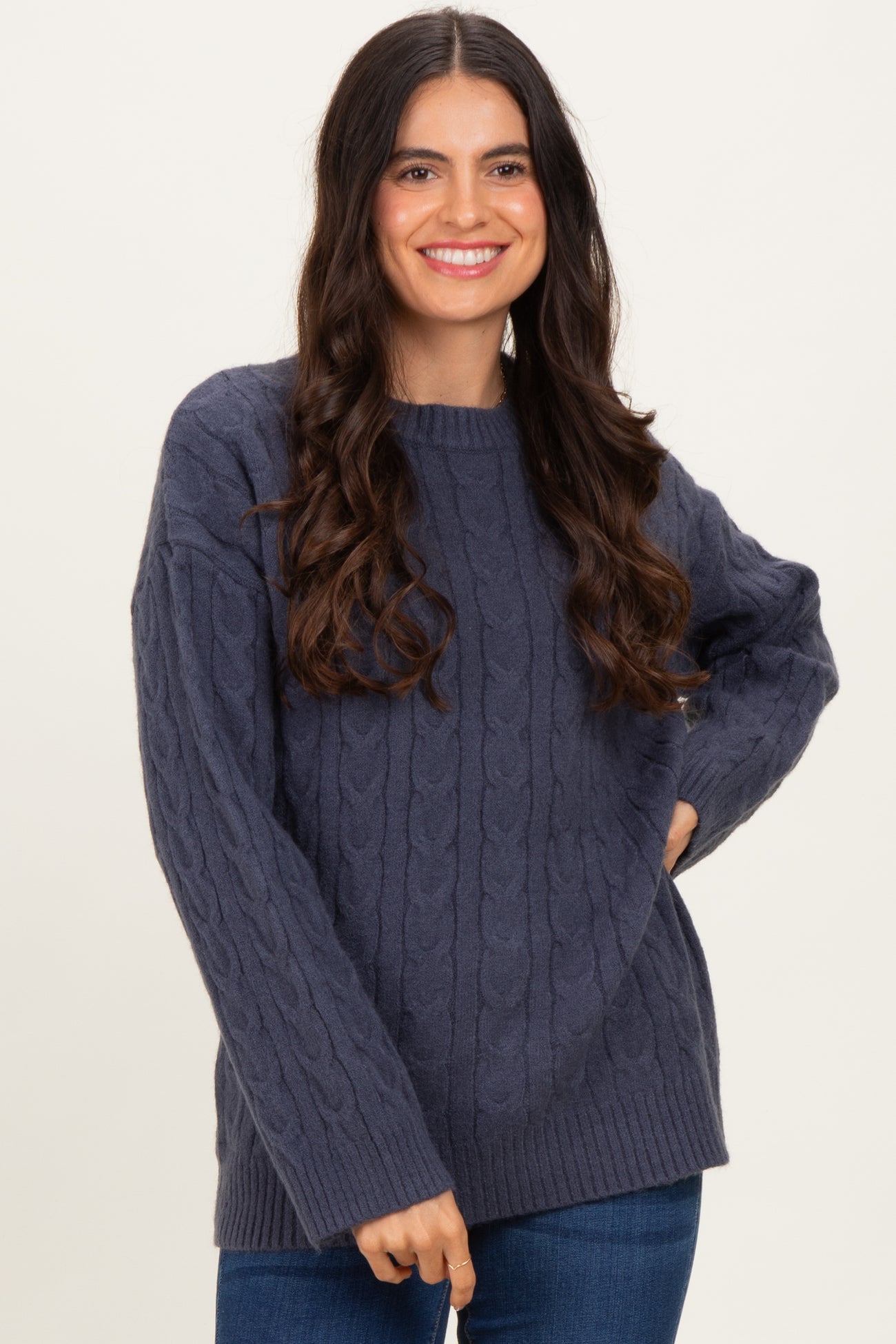 woman wearing a dark blue cable knit sweater with a relaxed fit and long sleeves, smiling at the camera