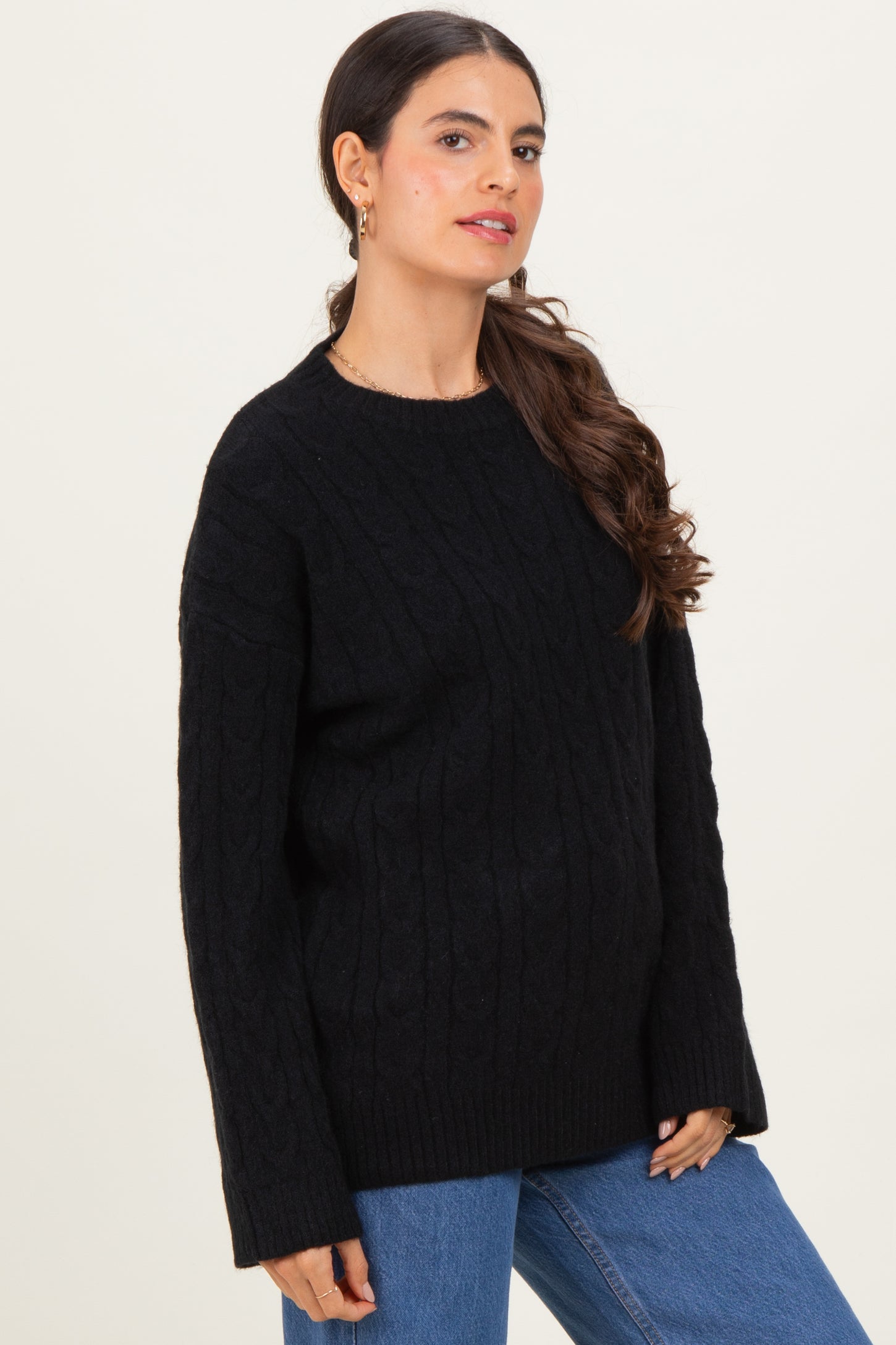 woman wearing a black cable knit sweater with a relaxed fit and long sleeves paired with blue jeans
