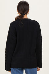 woman wearing a black cable knit sweater with long sleeves and a relaxed fit, shown from the back