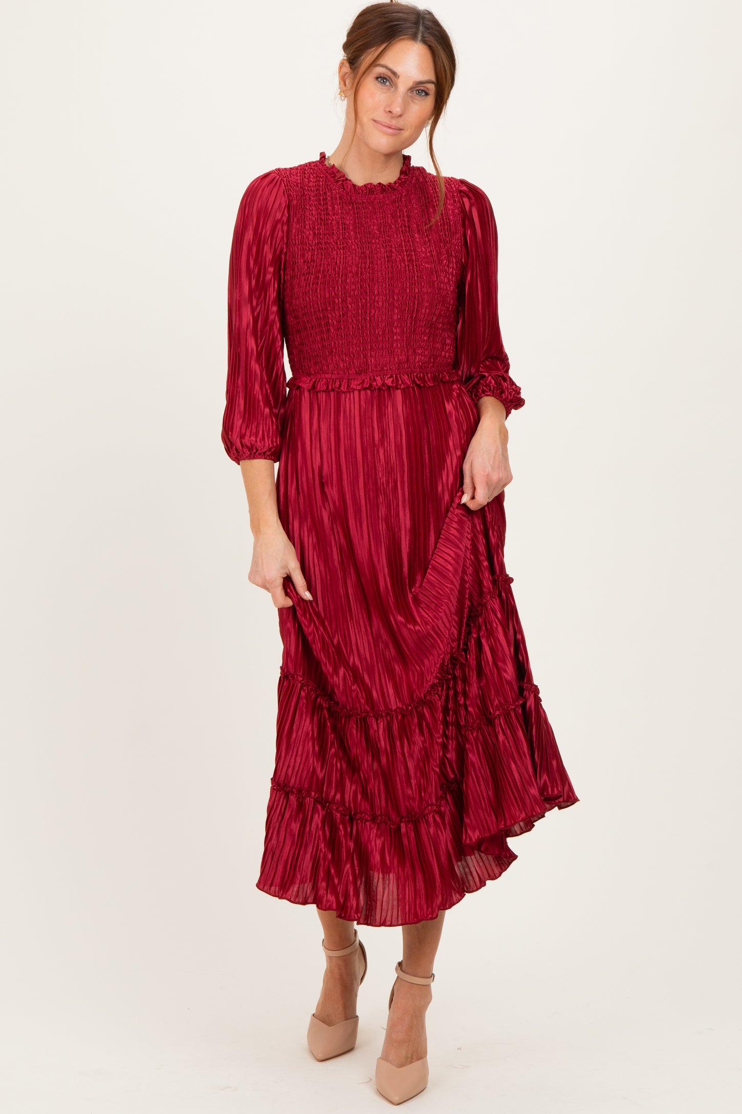 woman wearing a burgundy long sleeve pleated dress with ruffle details and a smocked bodice