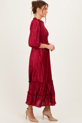 woman wearing a burgundy pleated maxi dress with a smocked bodice and tiered ruffle hem, styled with nude heels