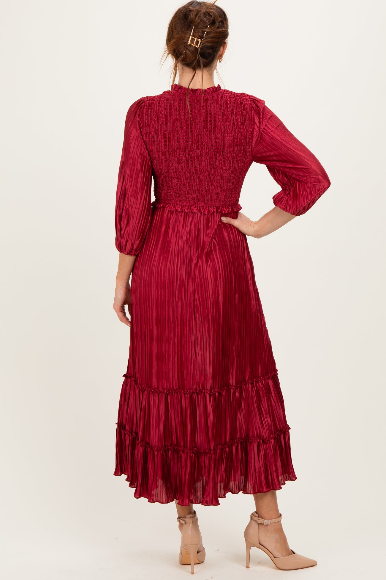 woman wearing a burgundy pleated midi dress with a smocked bodice and ruffle hem, seen from the back